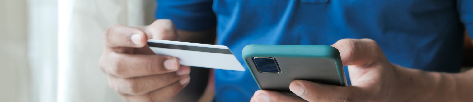 Close up of man holding debit card and cell phone