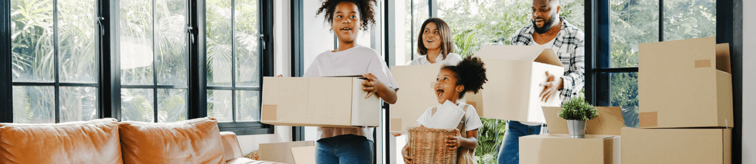 Family of four moving into a new home carrying boxes