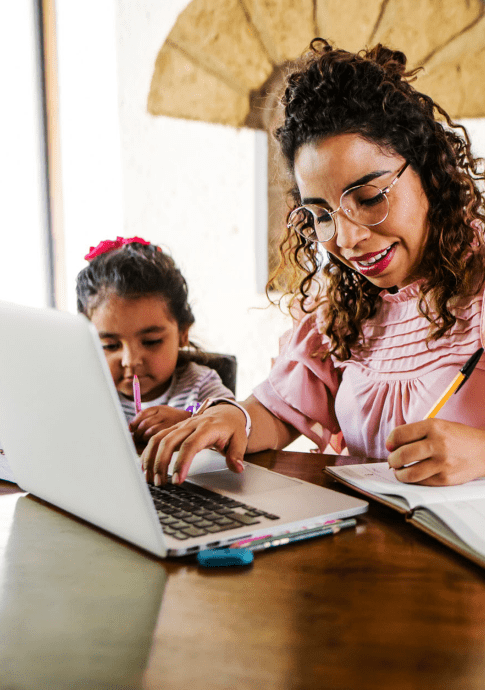 mother works on laptop with child playing