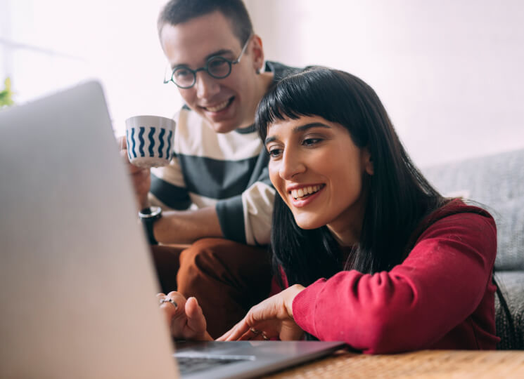 Young man and woman smiling and looking at a laptop