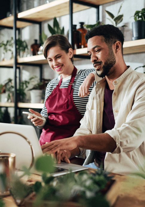 Male and female business owners working on bills on laptop.