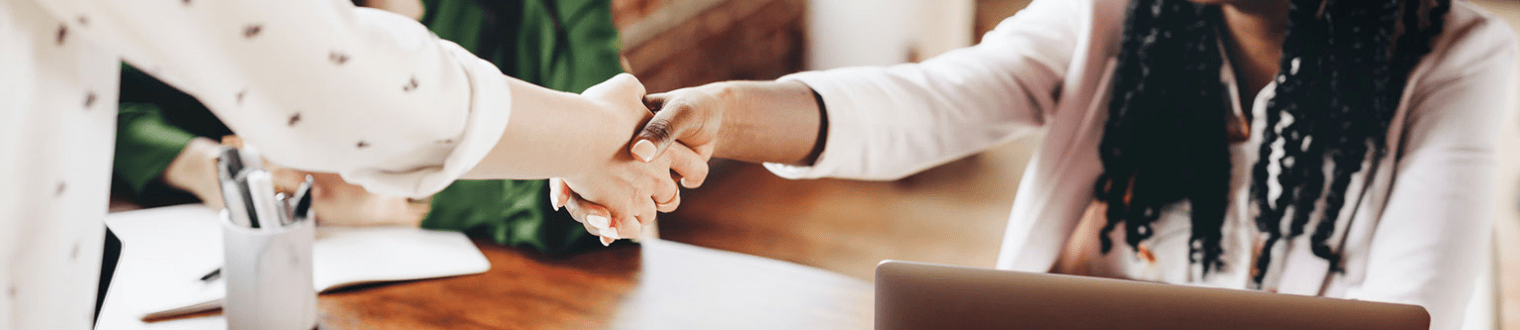 Two woman shaking hands in office.